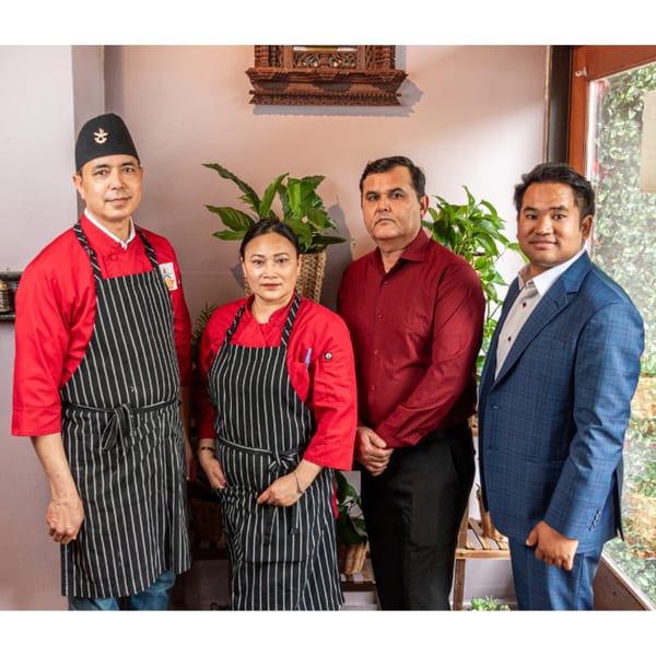 Four Bir Kitchen staff members, two chefs in red and two managers, stand together in the restaurant.