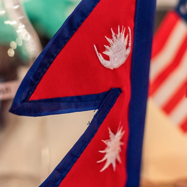 Close-up of a red and blue Nepali flag with a white embroidered sun and moon.
