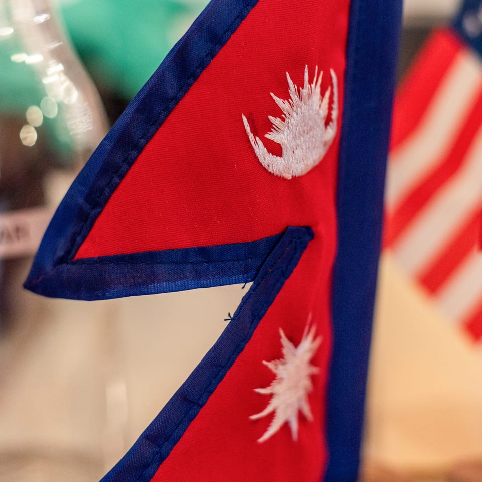 Close-up of a red and blue Nepali flag with a white embroidered sun and moon.